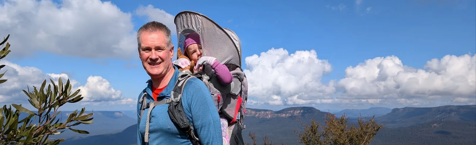 Dad carrying kid in a backpack on a hike