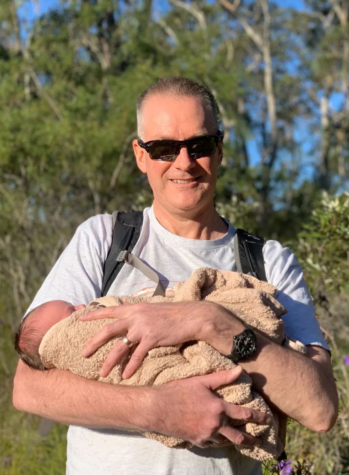 Dad carrying baby in a towel on a hike